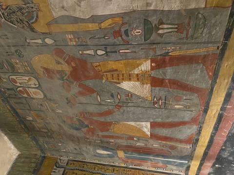 Ancient Egyptian wall mural depicting two figures surrounded by hieroglyphics in earthy tones inside a tomb.