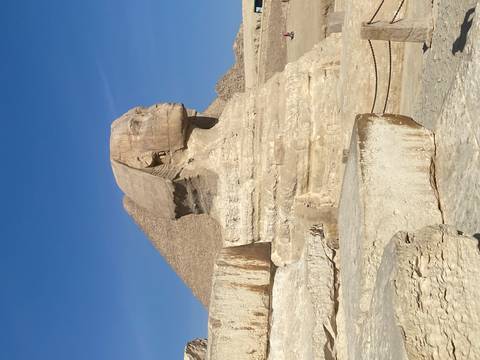 The Great Sphinx of Giza with the Pyramid of Khafre rising behind under a clear blue Egyptian sky.