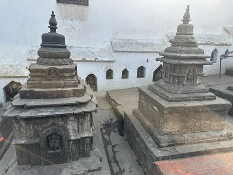 Weathered stone stupas and shrines in a quiet temple courtyard.