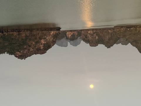 Dusk view of limestone karsts in Halong Bay under a rising full moon.