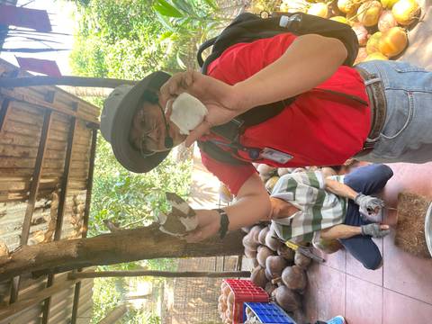 Local guide demonstrates a coconut product while wearing a microphone headset.