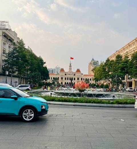 Bustling central square in Ho Chi Minh City with fountain and city hall behind.