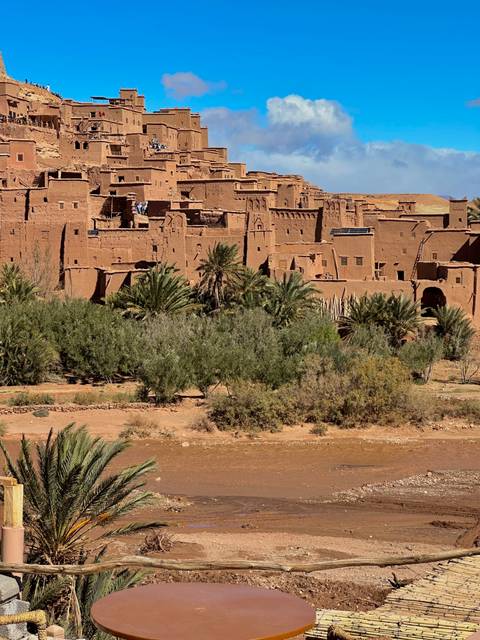 Historic earthen kasbah of Ait Benhaddou with palm groves in the foreground.