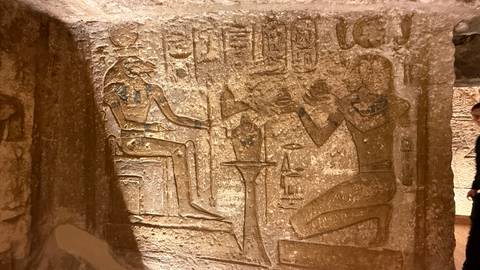Low-light photo of carved relief inside a narrow ancient tomb chamber.