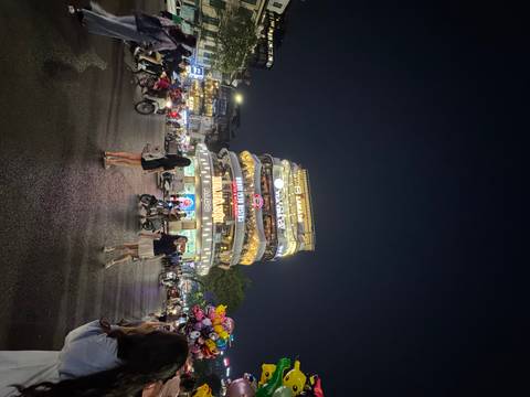 Bustling Hanoi night scene with illuminated multi-storey café and crowds of scooters crossing the intersection.