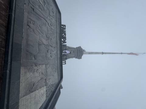 A foggy summit scene with a tall flagpole and engraved stone base at Fansipan 3,143 m.
