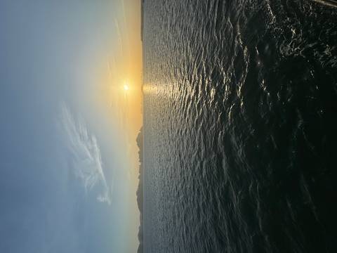 Golden sunset over calm waters dotted with distant limestone karsts in Halong Bay.