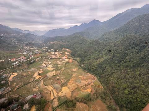 Wide drone panorama of terraced valleys and distant misty peaks in northern Vietnam.