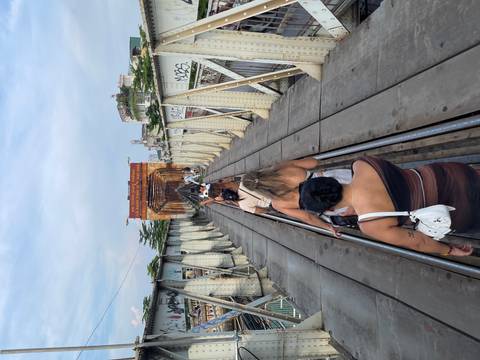 Travelers walk single-file along the narrow rail tracks of Hanoi’s historic Long Biên Bridge.