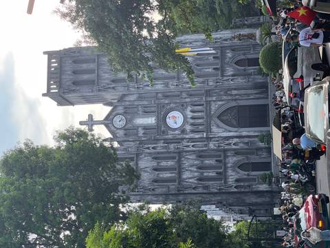 Neo-Gothic façade of St. Joseph’s Cathedral in Hanoi towering over busy traffic at dusk.