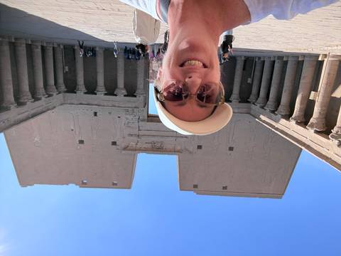 Selfie inside the grand courtyard of Edfu Temple with towering sandstone pylons engraved with deities.
