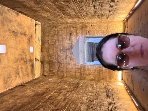Close-up selfie in a dimly lit temple chamber adorned with golden hieroglyphs.