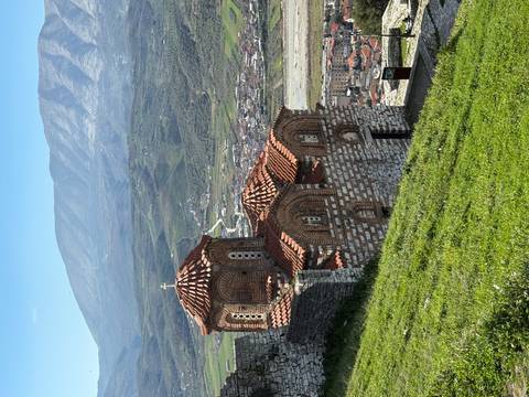 Byzantine-style hilltop church overlooking a green valley and town below.