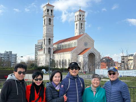 Tour group smiling in front of twin-towered church (duplicate scene).
