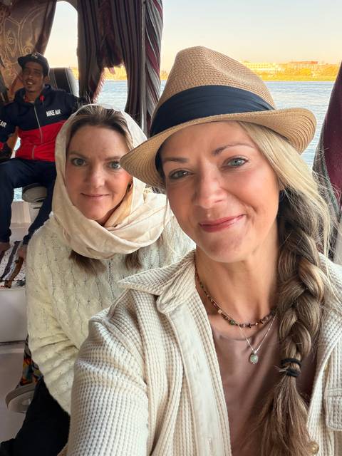 Two female travelers smiling for a selfie on a boat interior