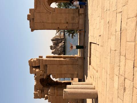 Traveler standing triumphantly among sandstone ruins overlooking the Nile