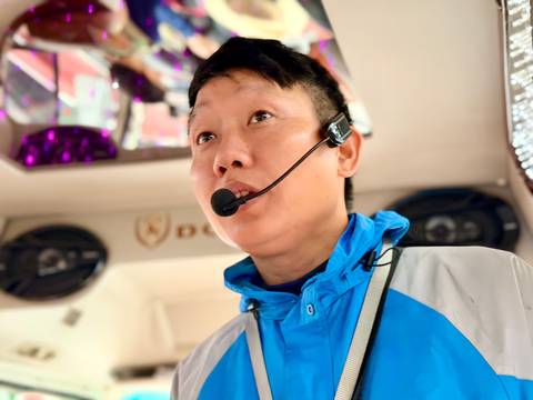Tour guide speaking into a headset microphone inside a tour bus.