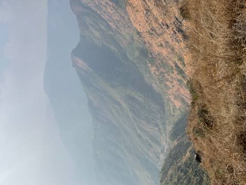 Hazy layered mountain ranges and a deep green valley seen from a high vantage point.