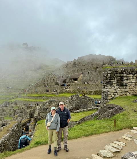 Smiling couple posing amid the misty stone terraces of Machu Picchu.
