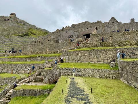 Wide view of Machu Picchu stone terraces with scattered visitors exploring.