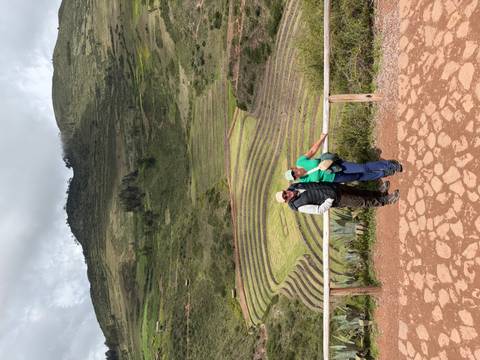 Couple standing before the circular agricultural terraces of Moray in Peru.