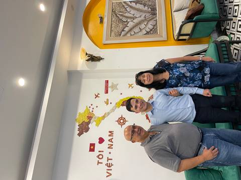 Indoor snapshot of a couple with their guide posing in front of a Vietnam map wall mural.