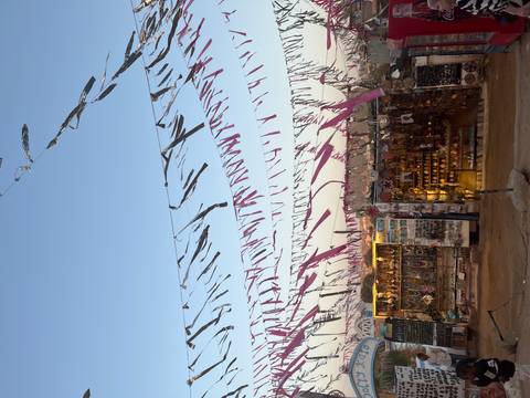 Colorful Nubian market stalls decorated with fluttering ribbons under a clear evening sky.