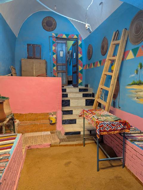 Colorful interior staircase of a Nubian-style house with blue, pink and geometric painted walls.