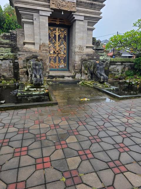 Courtyard with weathered stone elephant fountains, shallow water and small flower offerings.