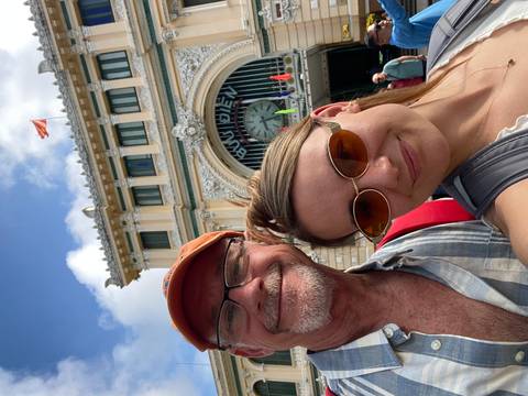 Selfie of two travelers smiling outside the ornate Saigon Central Post Office.