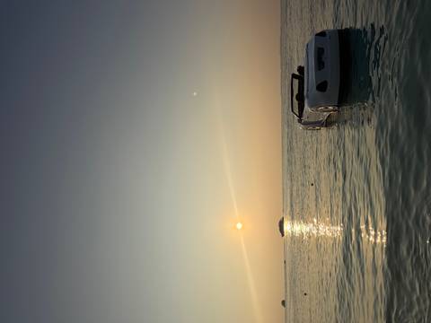 Serene seascape at dusk with a floating convertible pedal boat and distant yacht beneath a pastel sky.