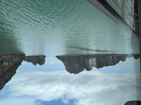Calm turquoise waters and limestone karst islands of Ha Long Bay viewed from a boat railing.