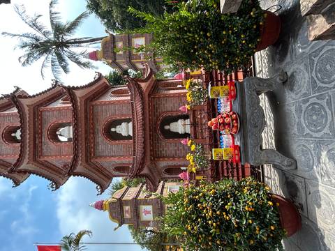 Brick pagoda tower with Buddha statues and festive fruit offerings arranged on a stone table in the courtyard.