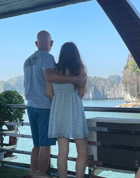 A couple embraces while admiring the limestone karsts of Halong Bay from a cruise deck.