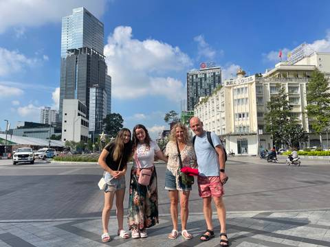 Family of four poses on a broad pedestrian boulevard with Ho Chi Minh City skyscrapers behind them.