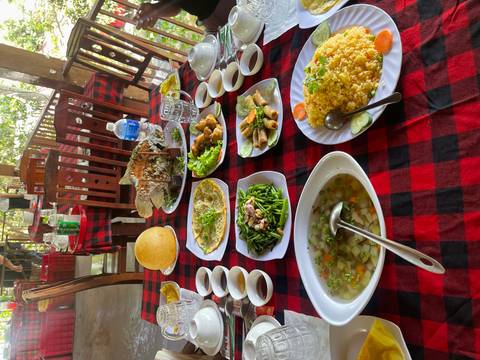 A colourful Vietnamese feast laid out on a checkered tablecloth inside a rustic open-air restaurant.