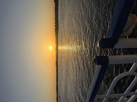 Golden sun setting over a wide calm river with shimmering reflection on the water surface