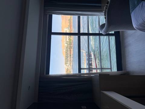 View from a hotel cabin window overlooking passing boats on a wide river under clear skies