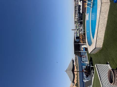 Sunny rooftop pool deck of a cruise ship with lounge areas overlooking desert river scenery