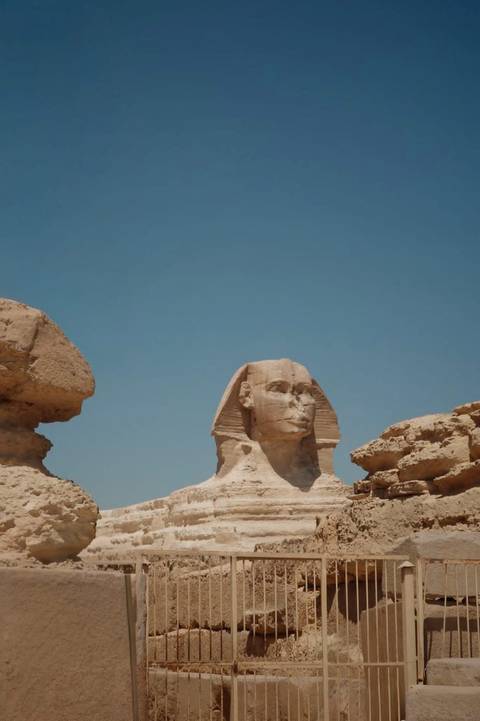 Iconic Great Sphinx head framed against a clear blue sky and sandstone blocks