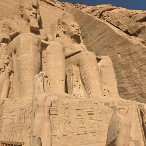 Close-up of colossal seated statues carved into the sandstone facade of Abu Simbel temple