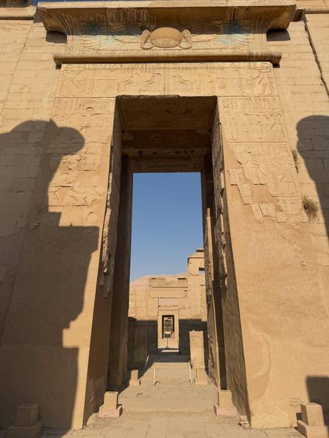 Stone doorway and hieroglyph-covered pillars framing a view of desert mountains beyond