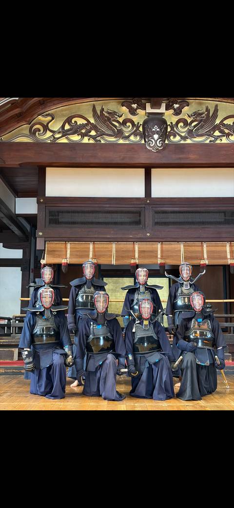 Display of six kendo armours with helmets and bamboo swords inside a traditional dojo.