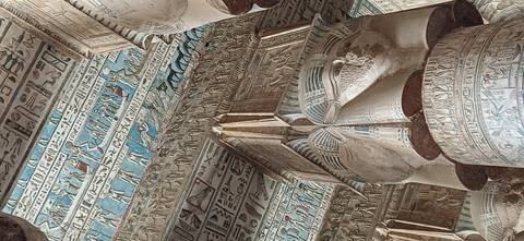 Ornately painted columns and blue astronomical ceiling inside an Egyptian temple