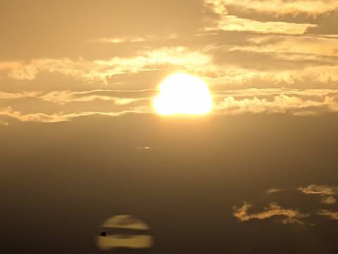 Glowing sun partially hidden by dramatic clouds at the horizon.