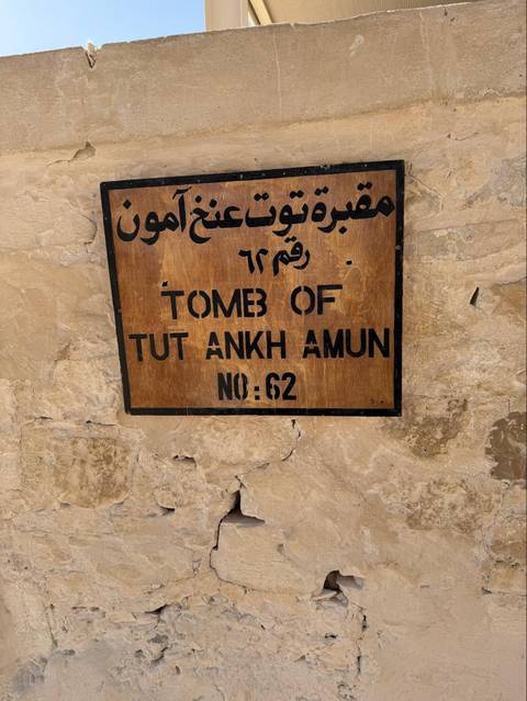 Wooden plaque identifying Tomb of Tutankhamun No. 62 on stone wall.