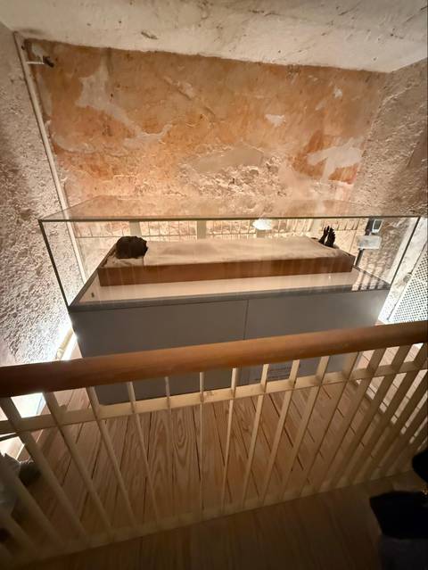 Glass case displaying mummified remains inside dimly lit Egyptian tomb.