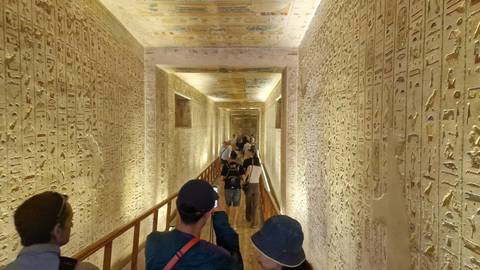 Visitors descend a richly decorated corridor inside a pharaoh’s tomb in the Valley of the Kings.
