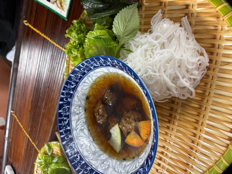 Vietnamese dish of bun cha with grilled pork in broth, rice noodles and fresh herbs