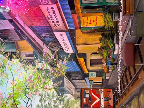 Colorful wall mural depicting Hanoi's train street with blooming trees and shop signs